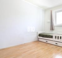 A bright room with a bed in a 3-room apartment, floor with wood decor.