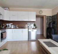 A bright kitchen with white cabinets and a wood-patterned floor in a three-room apartment.