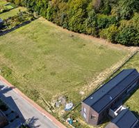 Aerial view of development plots in Borinka surrounded by greenery and a road.