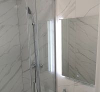 Bathroom with a shower and a sink in a 3-room apartment with marble-look tiles.