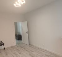 A room in a 3-room apartment with a wooden decor floor and a black chair.