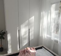 A bedroom with a large wardrobe in a 3-room apartment with white curtains.