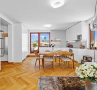 Interior of a 3-room apartment with a wooden decor floor, dining table, flowers in the living room.