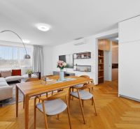 Dining area in a 3-room apartment with a wooden decor floor and a large window.