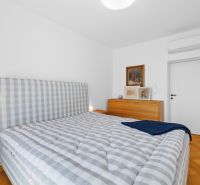 A bedroom with a large bed, a dresser, and a wooden decor floor in a 3-room apartment.
