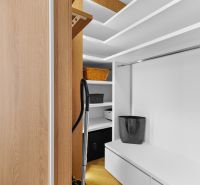 Wardrobe with shelves and a rod, standing vacuum cleaner, floor with wooden decor.