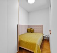 A bedroom with an upholstered headboard and a wooden decor floor in a 3-room apartment.