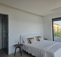 A bedroom in a 4-room apartment with a bed and a view of greenery through a large window.