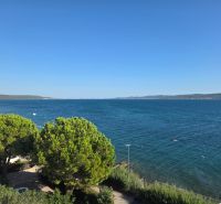 Sea view from a 4-room apartment in Sukošan, surrounded by green trees and a clear sky.