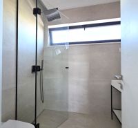 A bathroom with a glass shower and a sink in a 4-room apartment.