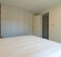 Bedroom with wardrobes, bed, and open doors in a 4-room apartment.