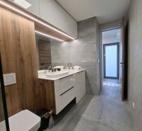 Bathroom in a 2-room apartment with a bathtub, wooden decor, and light tiles.