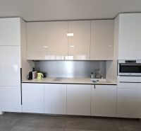A kitchen in a 2-room apartment with a glossy white kitchen unit and built-in appliances.