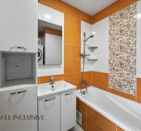 A bathroom in a 2-room apartment with a bathtub and orange tiles.
