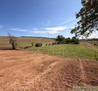 A plot for living in a village surrounded by grass and fields. Treeless landscape on the horizon.