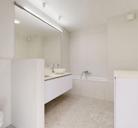 A bathroom with a shower, sinks, and a mirror in a 3-room apartment.