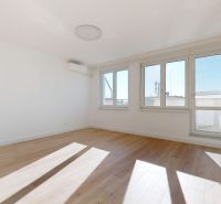 A bright room with wood-patterned flooring and large windows in a three-room apartment.