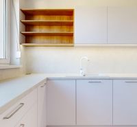 A kitchen in a 3-room apartment with gray cabinets and wooden shelves by the window.