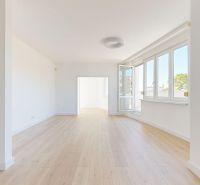 A bright living room with large windows and a wooden decor floor in a 3-room apartment.