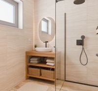 A bathroom with a sink on a wooden counter and a shower in a family house.