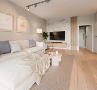 Living room in a family house with a white couch, table, and wooden decor flooring.