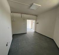Interior space for rent with outlets and gray flooring in warehouses and halls.