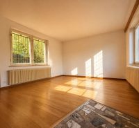 A bright room in a cottage with a wooden decor floor and large windows.