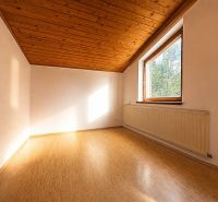 A room in a cottage with a wooden decor floor and a sloped ceiling.