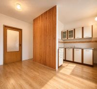 A kitchenette in a cottage with a wooden decor floor and a window.