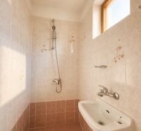 Bathroom in a cabin with ceramic tiles and a shower, floor with wooden decor.