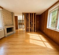 Interior of a cabin with wooden floor decor, a fireplace, and stairs leading to the upper floor.