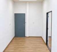 Room with closed doors in an office, floor with wooden decor, white walls.