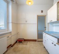 A kitchen in a 2-room apartment with white cabinets and a large window.