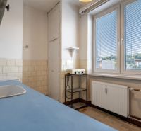 A kitchen with white tiles, a blue countertop in a 2-room apartment, a large window, simple interior.