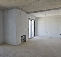 Interior of an empty room with a concrete ceiling and a large window in a 3-room apartment.