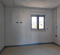 Empty room in a 3-room apartment with a large window and white walls.