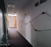 Offices with graphic design on the wall and a corridor with a carpeted surface.