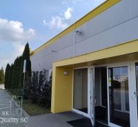 Exterior of a building in Senec with a parking lot and a yellow entrance to the offices.