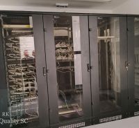 Server cabinets in offices with network cabling and the mirror reflection of people.