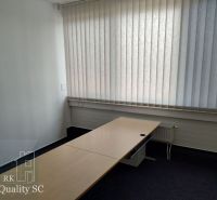 A bright office with a long table, blinds, and carpet.