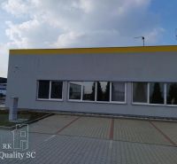 Offices in Senec with an outdoor parking lot, gray facade, and blue sky.