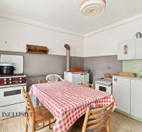 A kitchen in a family house with a kitchen unit, a stove, and a table with a checkered tablecloth.
