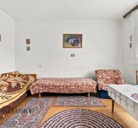 A room in a family house with beds, rugs, and a floor with a wooden decor.