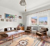 A bright living room with a sofa, armchairs, a table, and rugs in a family house.