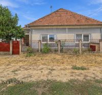 A family house in Bátorove Kosihy with a red roof and fence. Dried lawn.