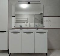 A bathroom with a double sink in a two-room apartment, white cabinet, large mirror.