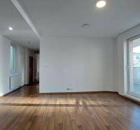 Living room in a two-room apartment with a wooden decor floor and large windows.