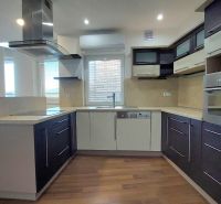 A kitchen in a 2-room apartment with a wood-patterned floor and built-in appliances.