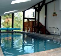 Interior of a holiday apartment with a wood-patterned floor and an indoor pool.