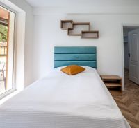 Single bed in a holiday apartment with a wooden decor floor and a large window.